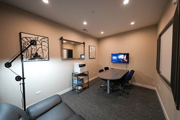 A conference room with a table, chairs, and a television.